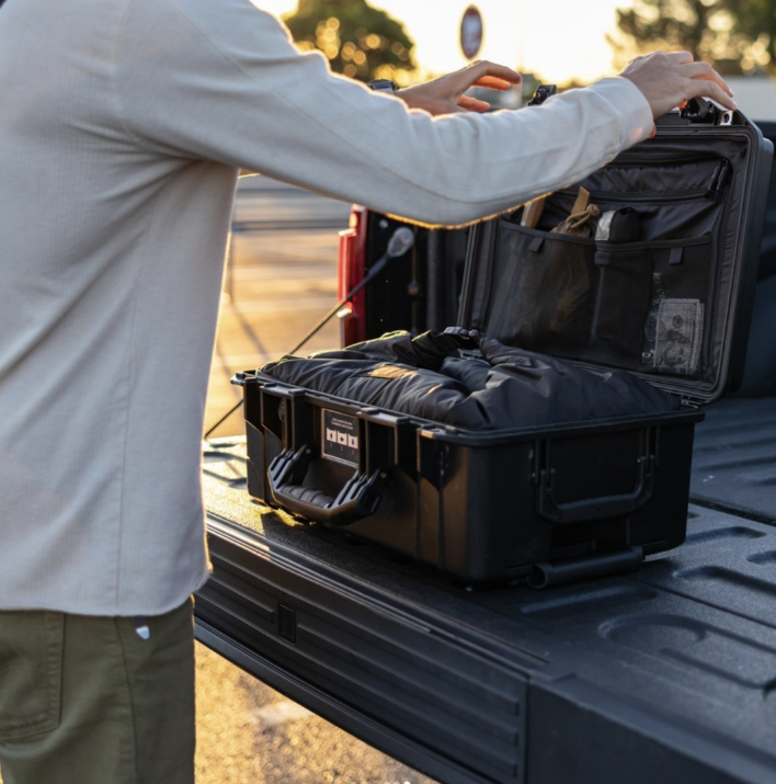 Person closing Pelicase containing Faraday Liner on a truck bed during sunset.