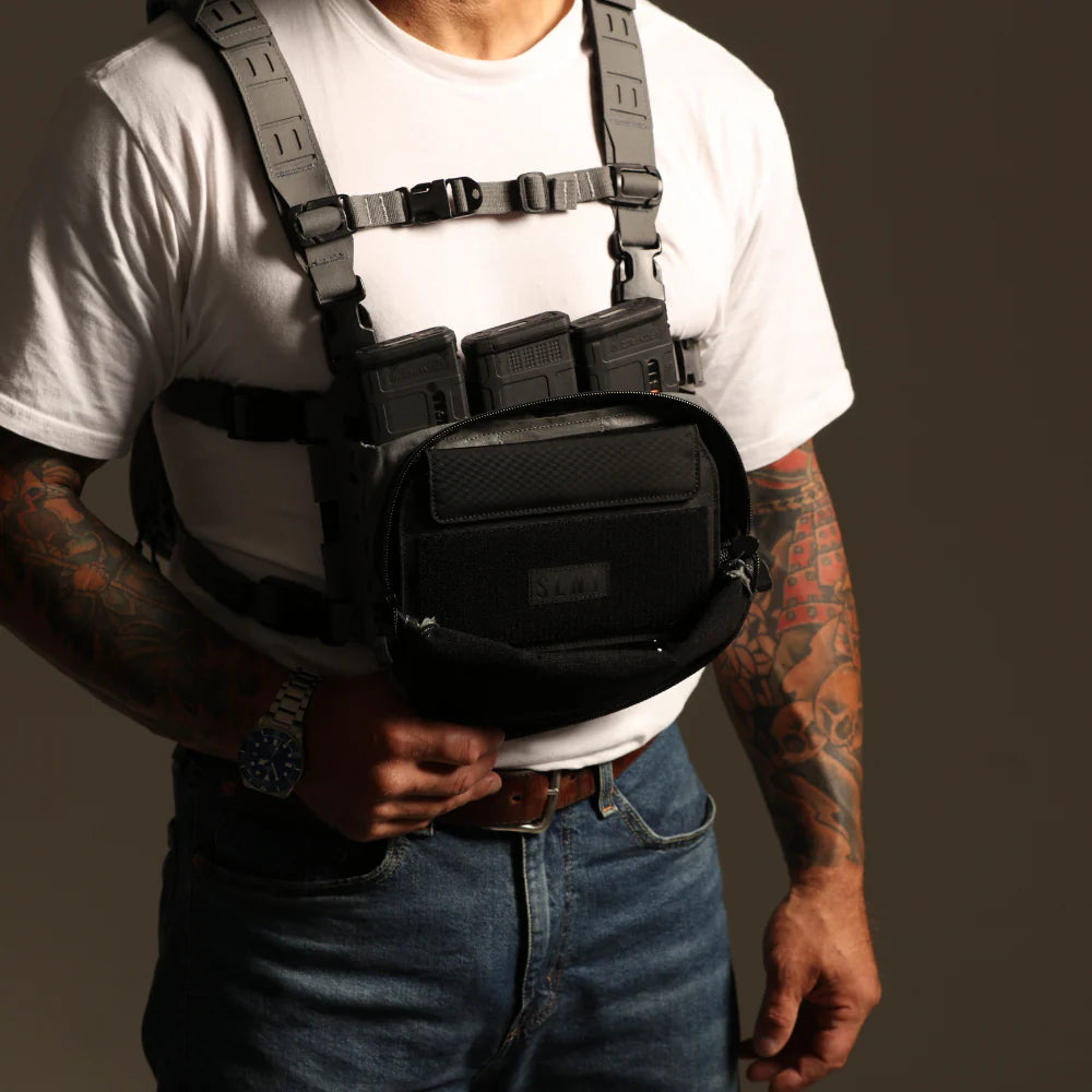 Person wearing a tactical vest with SLNT Faraday pouch on a plain background
