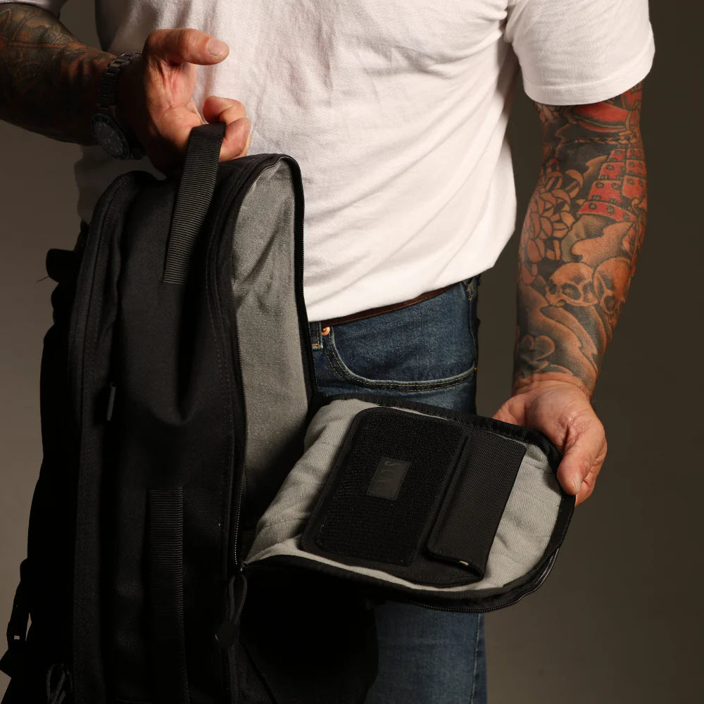 Person holding an open Faraday backpack with a SLNT Faraday Modular Insert attached on the inside surface
