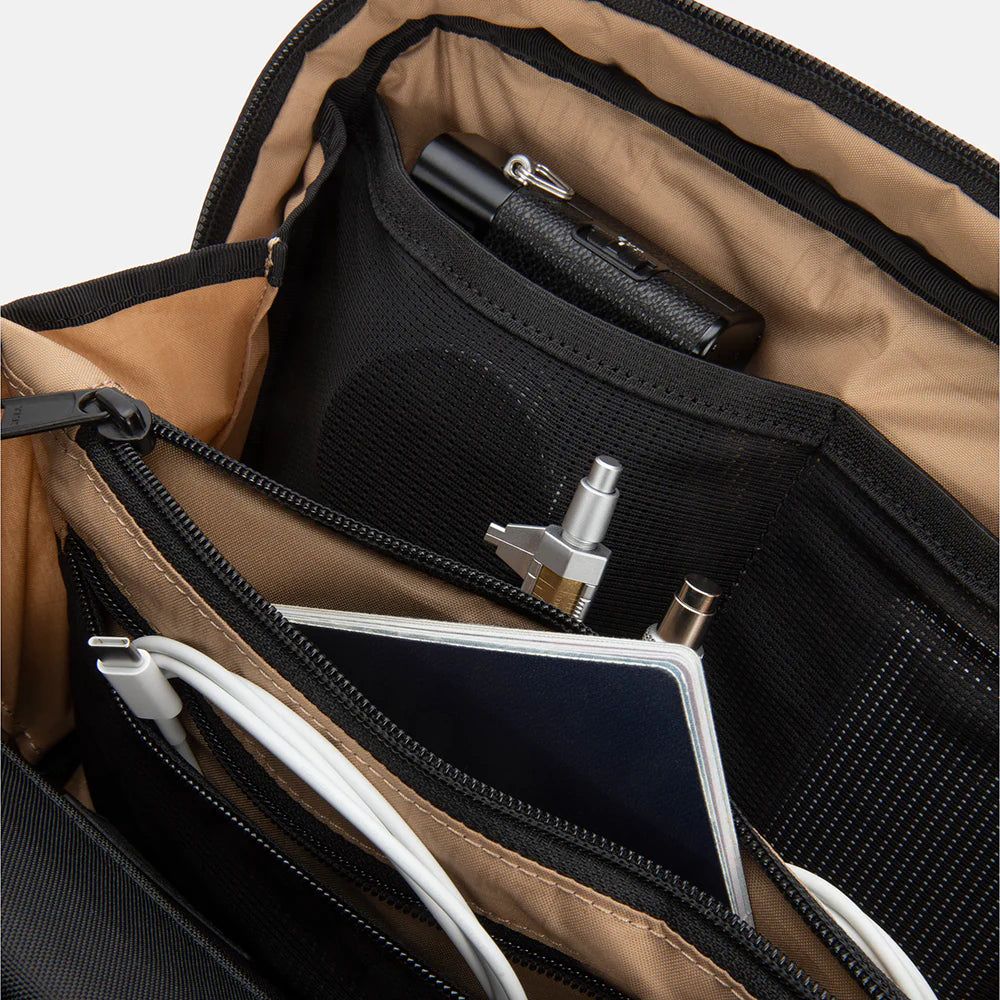 Close-up of opened SLNT E3 Faraday Crossbody Organizer Bag with items such as a camera, pens and notepads tucked into the pockets inside